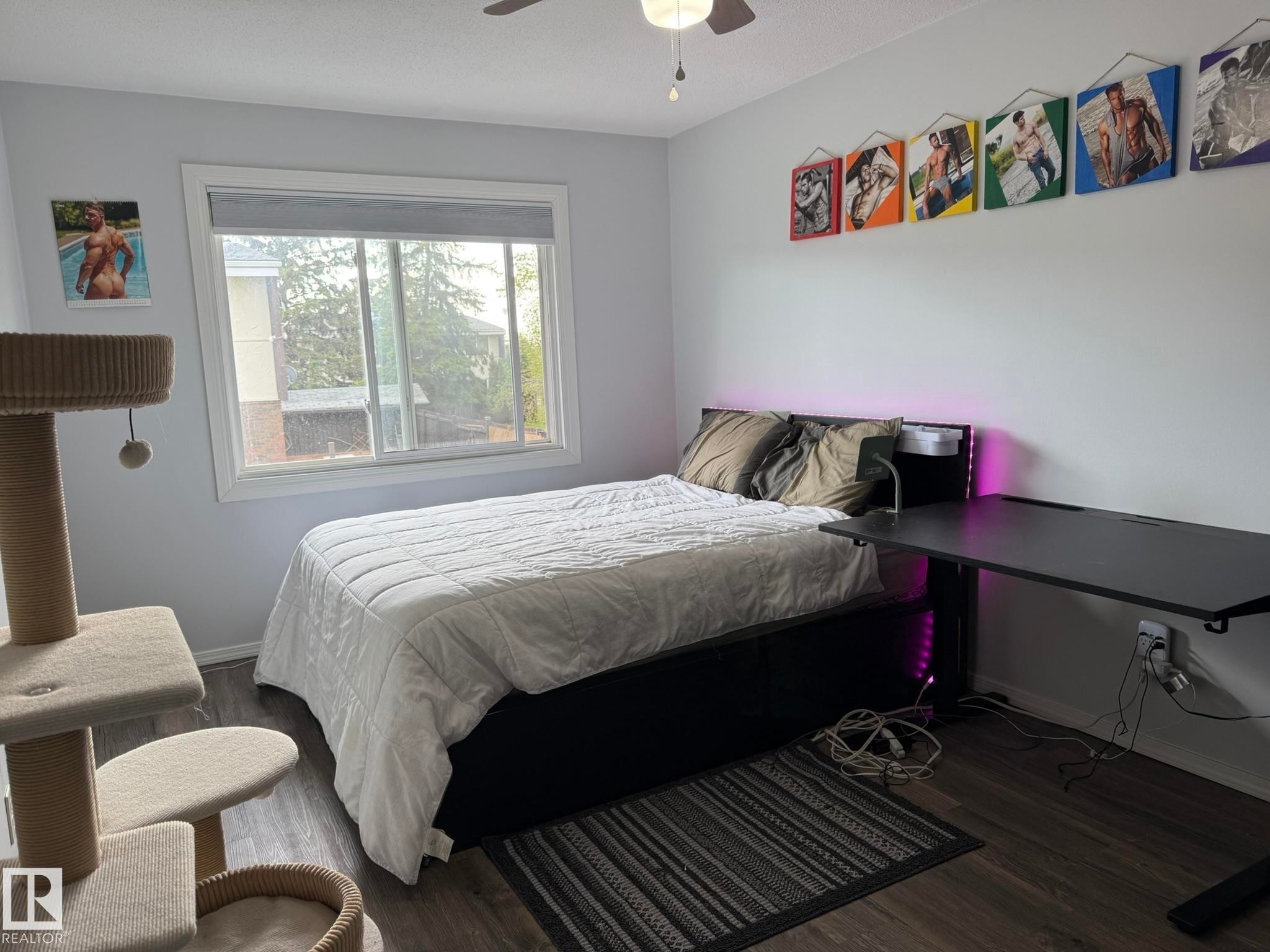 Primary Bedroom featuring VINYL PLANK FLOORING, a ceiling fan, and a large window with roller shades - 166 Roseland Village, Edmonton, AB - Indoor Photo Showing Bedroom