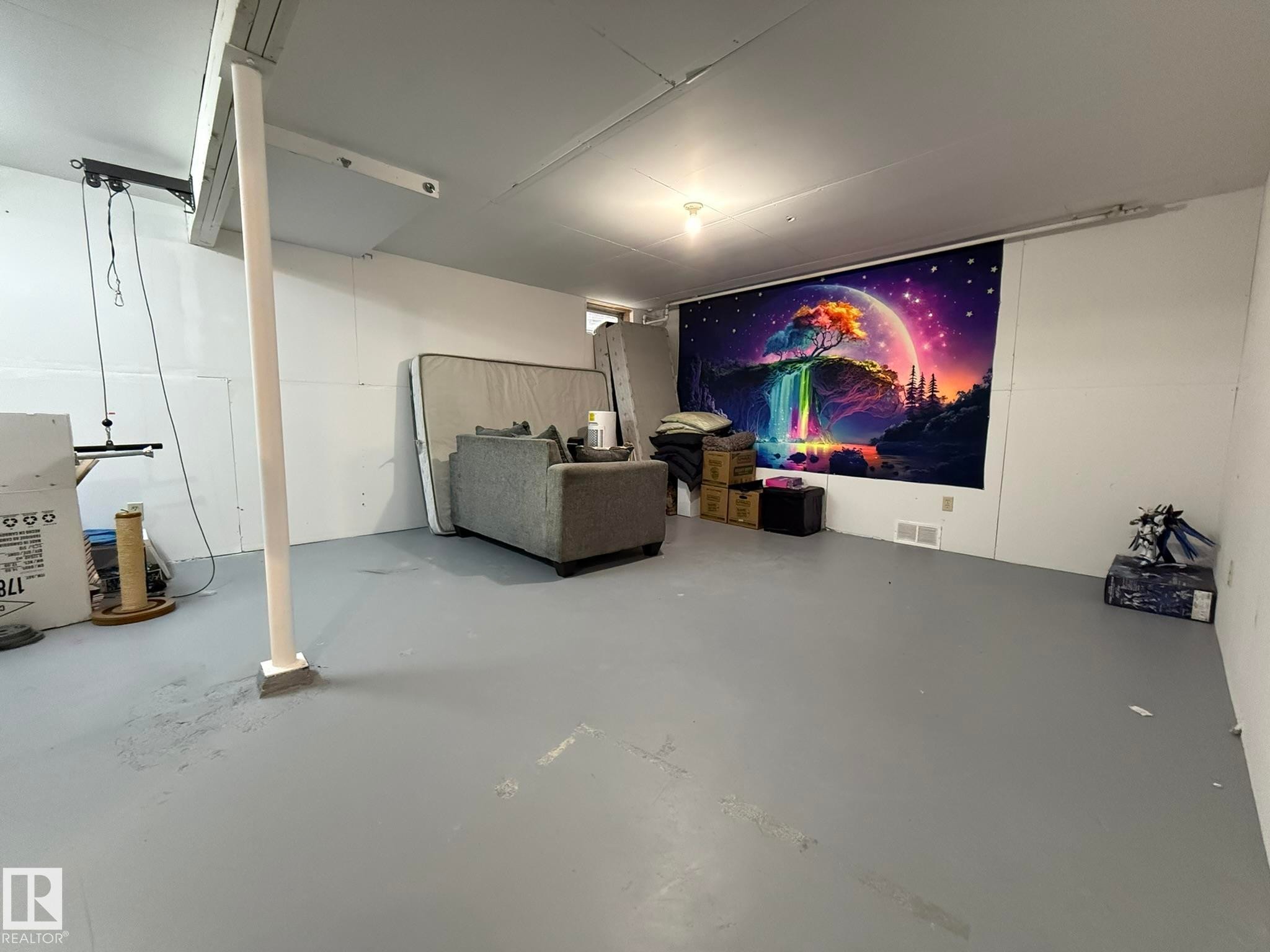 Unfinished basement featuring painted concrete flooring, white walls, and exposed ceiling joists - 166 Roseland Village, Edmonton, AB - Indoor