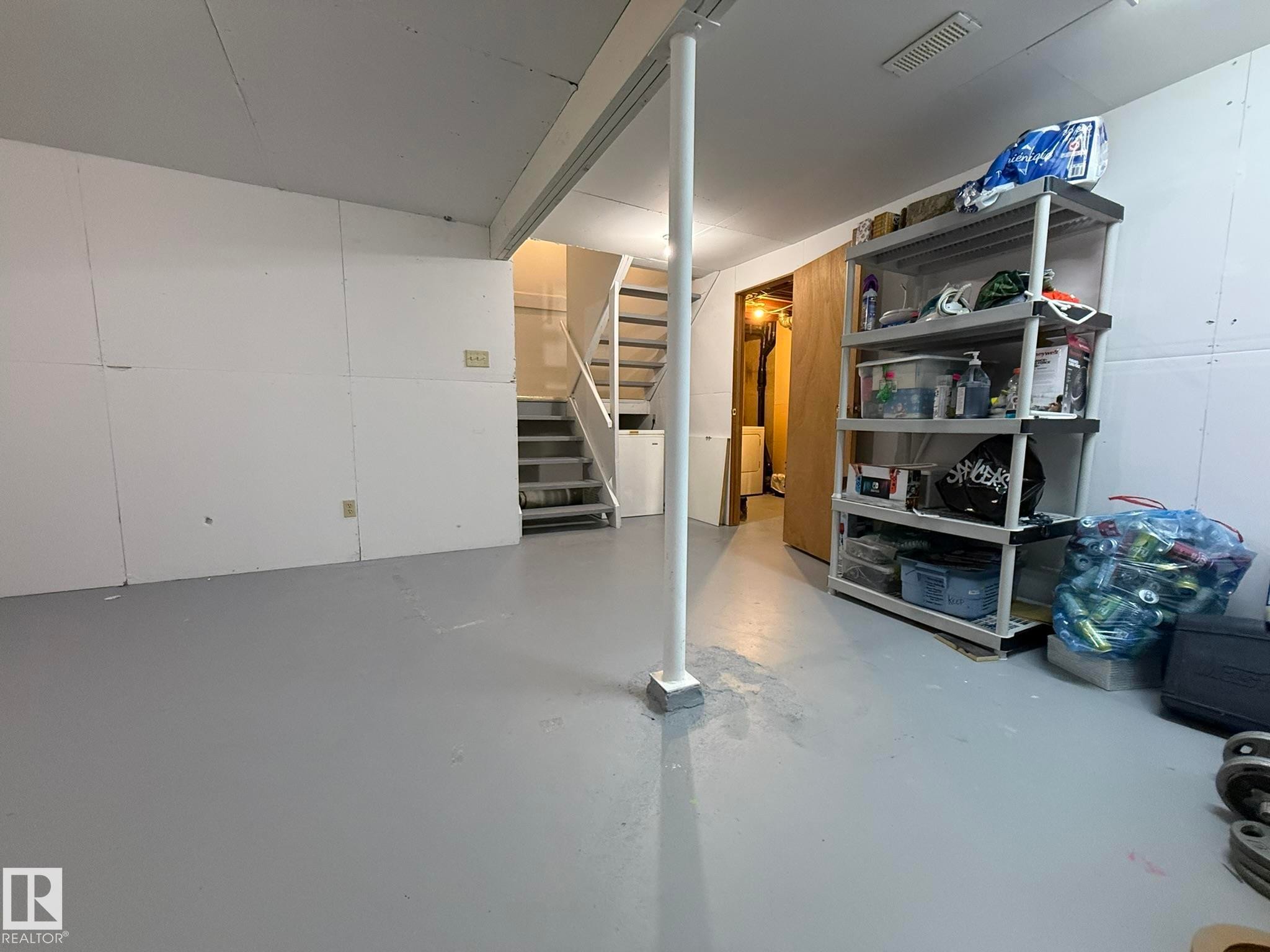 Expansive lower-level space featuring painted concrete flooring, white paneled walls, and a recessed ceiling vent - 166 Roseland Village, Edmonton, AB - Indoor Photo Showing Garage