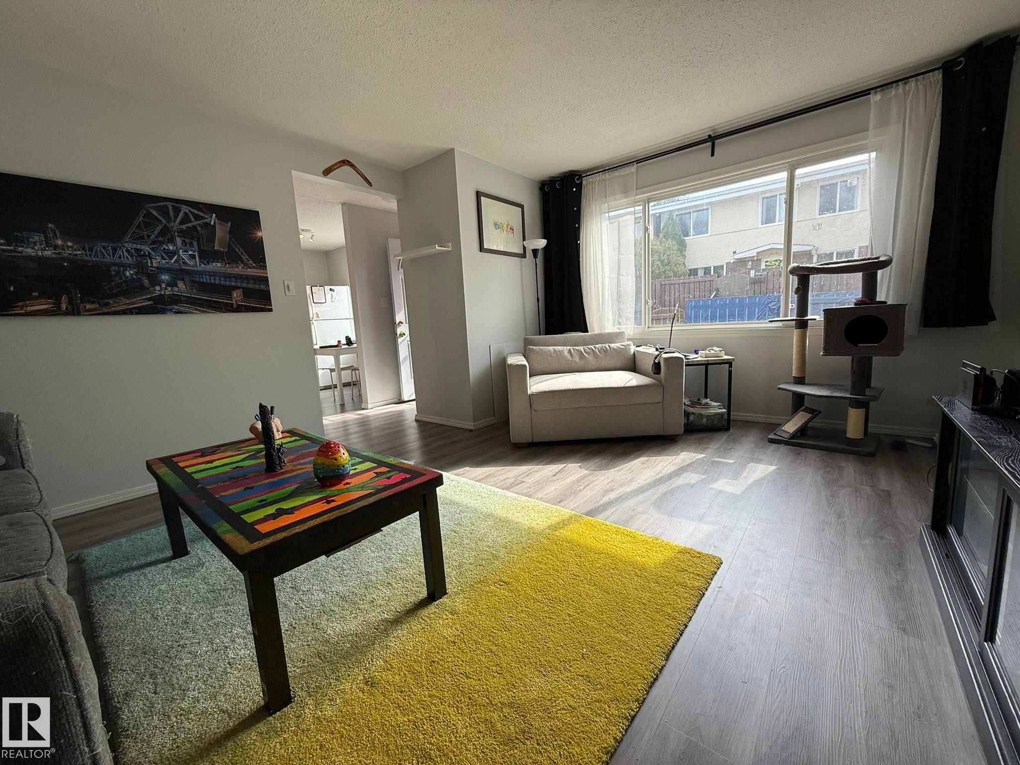 Living area with light-toned wall paint and wood-finish flooring - 166 Roseland Village, Edmonton, AB - Indoor Photo Showing Living Room