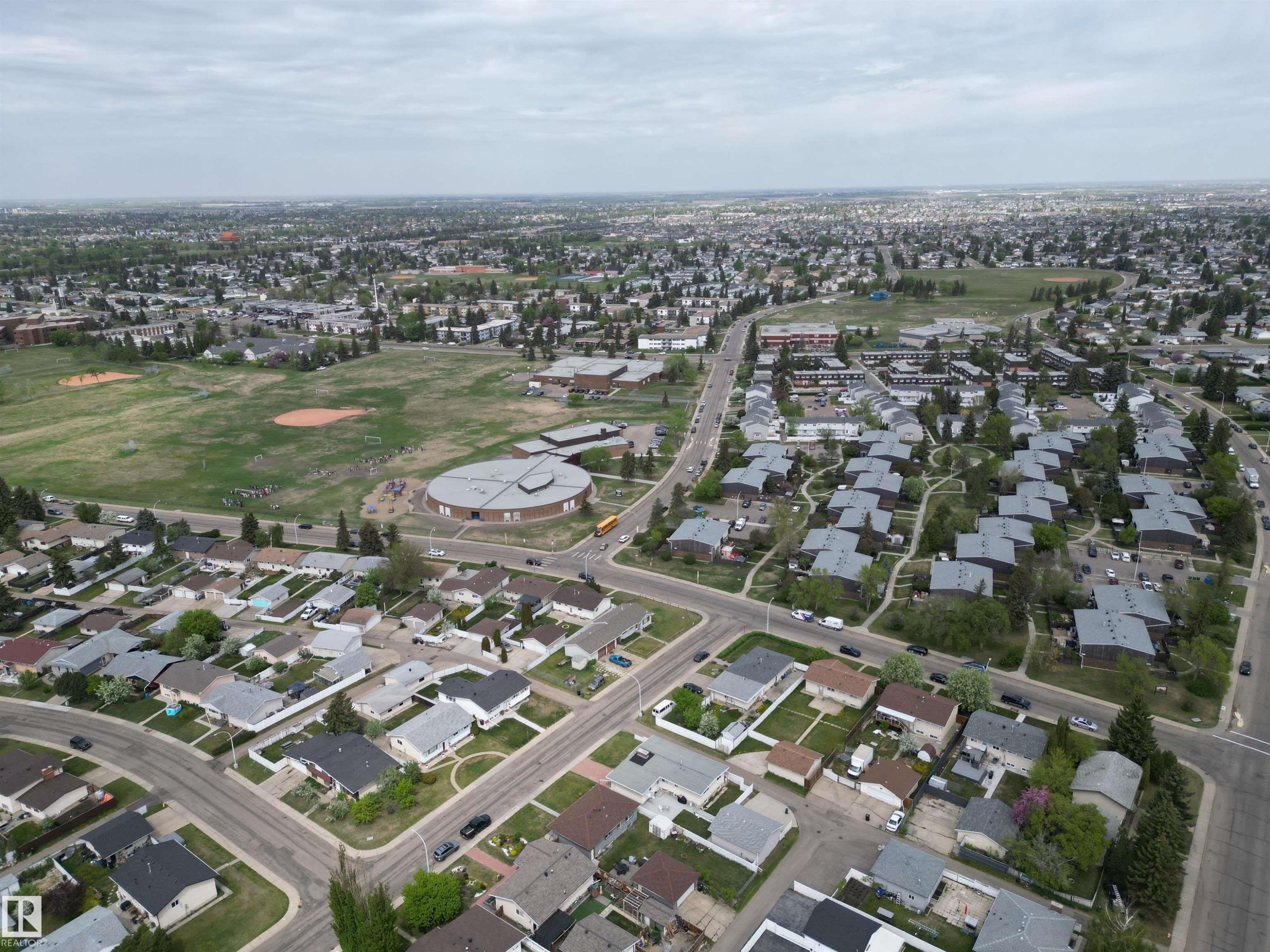 Expansive aerial panorama showcasing a residential district with a variety of housing styles, established tree-lined streets, and a large central green space - 166 Roseland Village, Edmonton, AB - With View