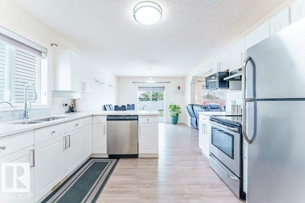 Modern kitchen featuring white cabinetry, stainless steel appliances, wood-finish flooring, and a window above the sink - 3525 22 Street, Edmonton, AB - Indoor Photo Showing Kitchen With Stainless Steel Kitchen