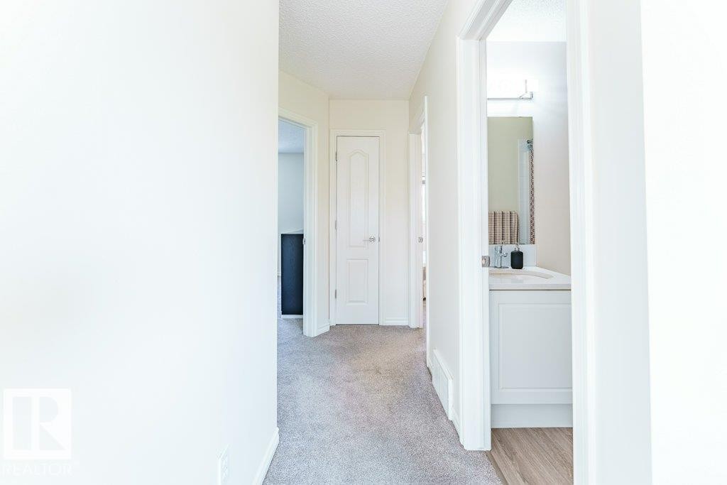Hallway with light gray carpeting, white baseboards, and white painted walls - 3525 22 Street, Edmonton, AB - Indoor Photo Showing Other Room