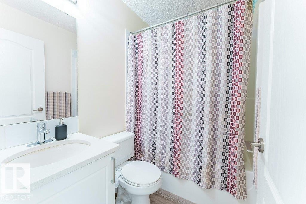 Bathroom featuring a white vanity with an integrated sink, chrome faucet, toilet, and a shower/tub combination - 3525 22 Street, Edmonton, AB - Indoor Photo Showing Bathroom