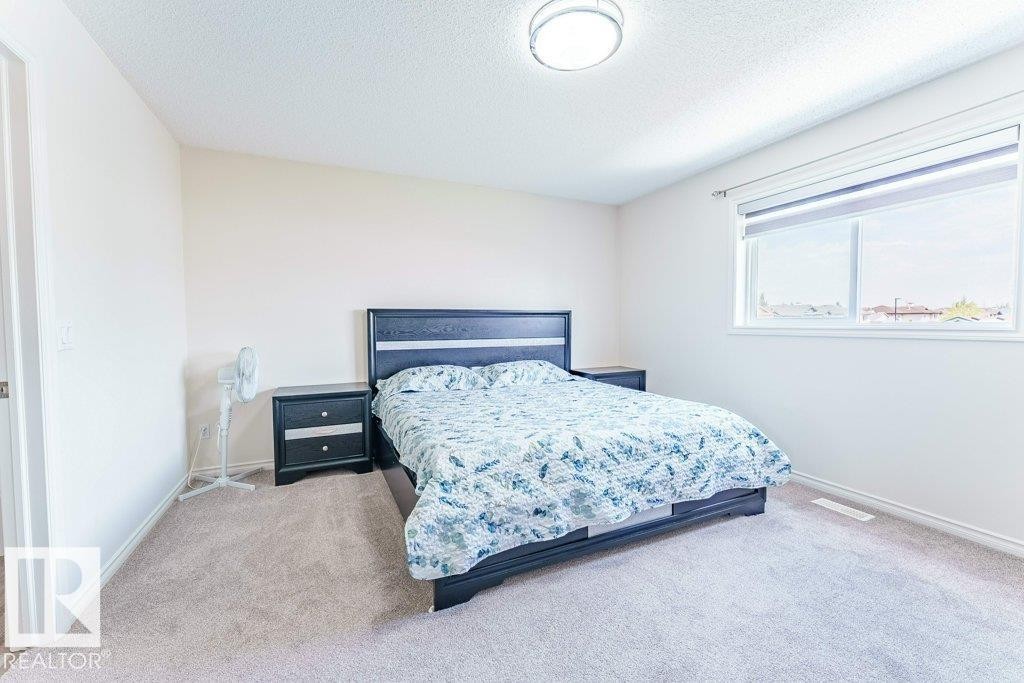 Spacious room featuring neutral carpeting, light-toned walls, and a large window with roller shades - 3525 22 Street, Edmonton, AB - Indoor Photo Showing Bedroom
