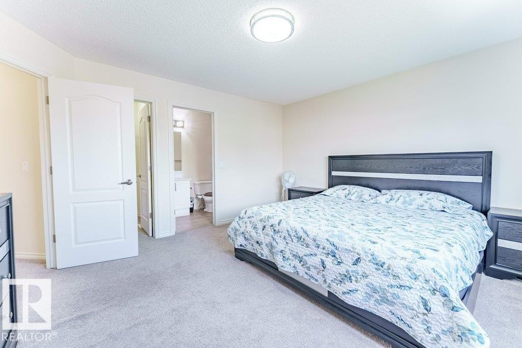 Carpeted room featuring a white interior door, a bathroom entrance with a vanity and toilet visible, and a ceiling-mounted light fixture - 3525 22 Street, Edmonton, AB - Indoor Photo Showing Bedroom