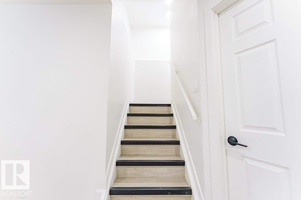 Staircase featuring light-toned treads with dark risers, white wall paneling, and a corresponding white handrail - 3525 22 Street, Edmonton, AB - Indoor Photo Showing Other Room