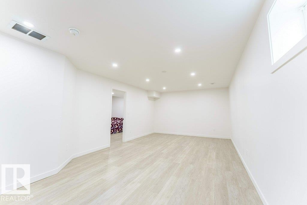 Spacious room featuring light wood-finish flooring, recessed lighting, and a white color palette - 3525 22 Street, Edmonton, AB - Indoor Photo Showing Other Room