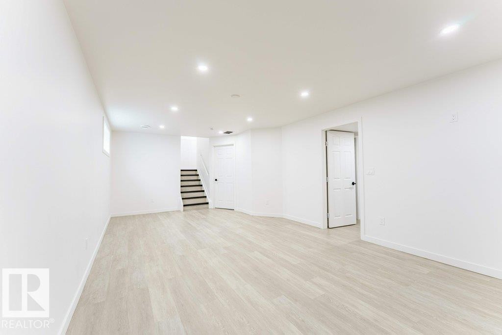 Spacious room featuring light wood-finish flooring, recessed lighting, and crisp white walls - 3525 22 Street, Edmonton, AB - Indoor