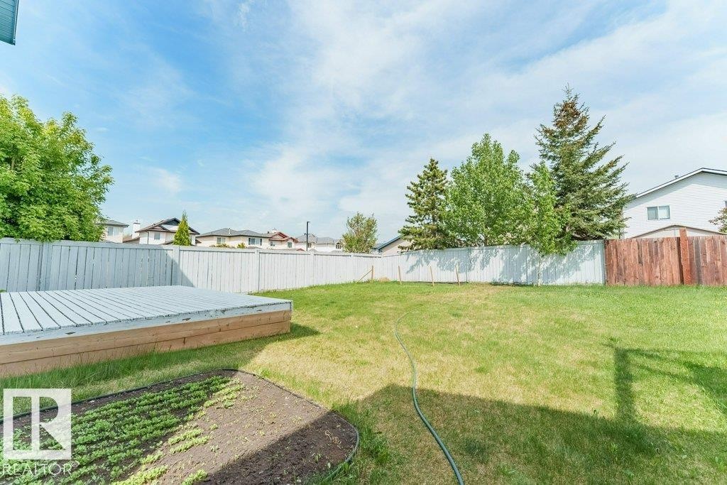 Expansive backyard featuring a large grass lawn, a low-profile wood deck, and a planted garden bed - 3525 22 Street, Edmonton, AB - Outdoor With Backyard