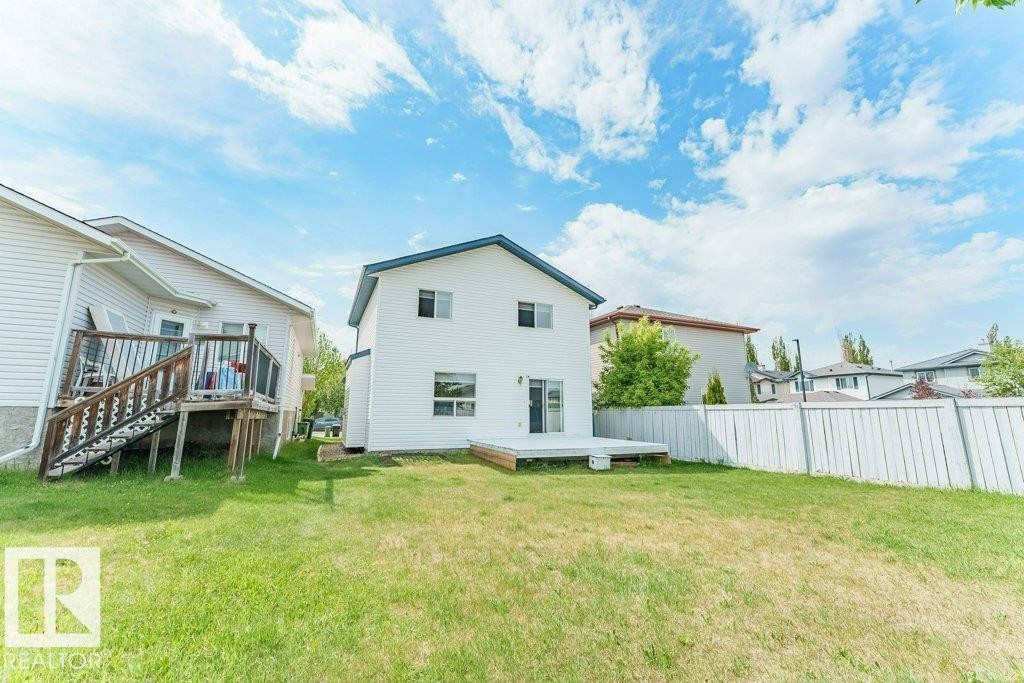 White siding exterior featuring a blue roofline and a lower-level deck - 3525 22 Street, Edmonton, AB - Outdoor With Deck Patio Veranda