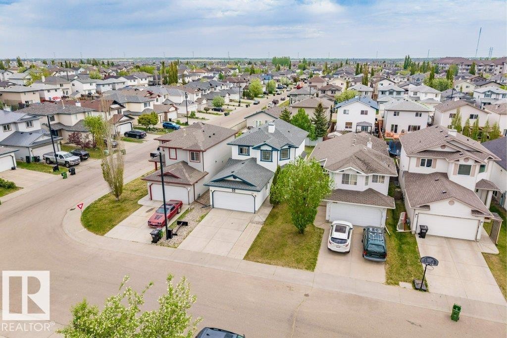 Residential streetscape featuring single-family homes with attached garages, concrete driveways, and green lawns - 3525 22 Street, Edmonton, AB - Outdoor With View