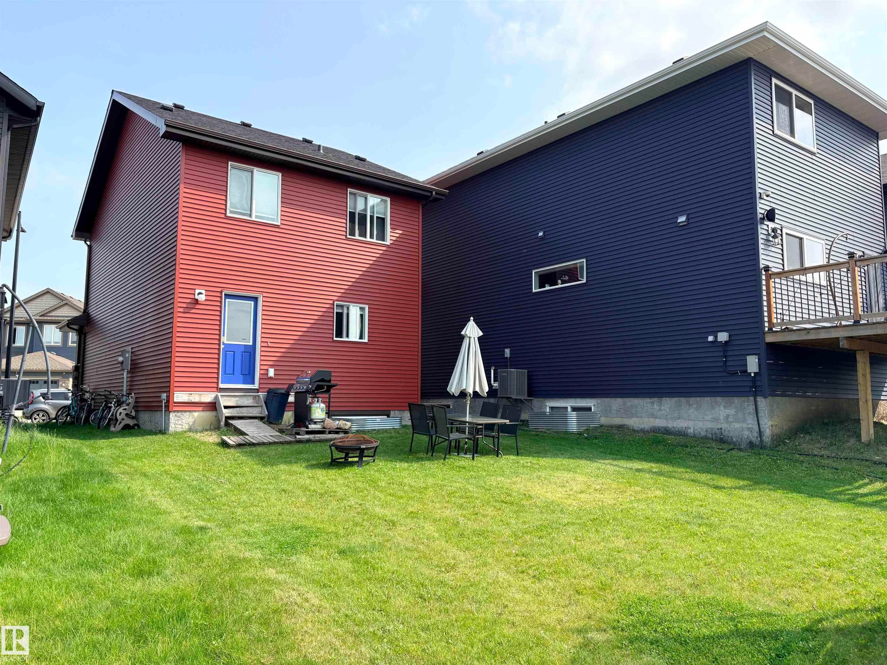 Expansive green lawn with two distinct residential structures featuring horizontal siding - 2424 Wonnacott Court, Edmonton, AB