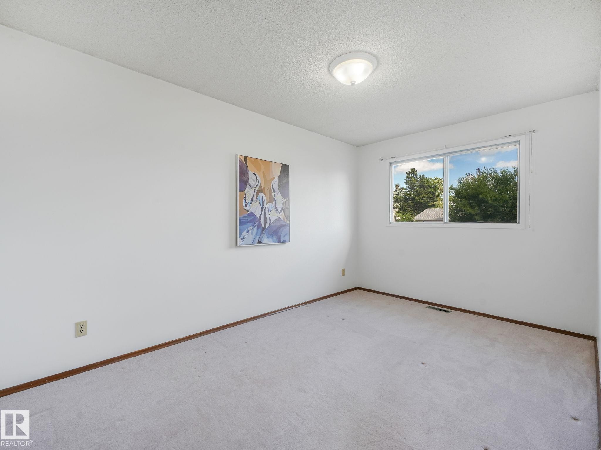 Bright room with a large window, neutral carpeting, and white walls - 15011 72A Street, Edmonton, AB