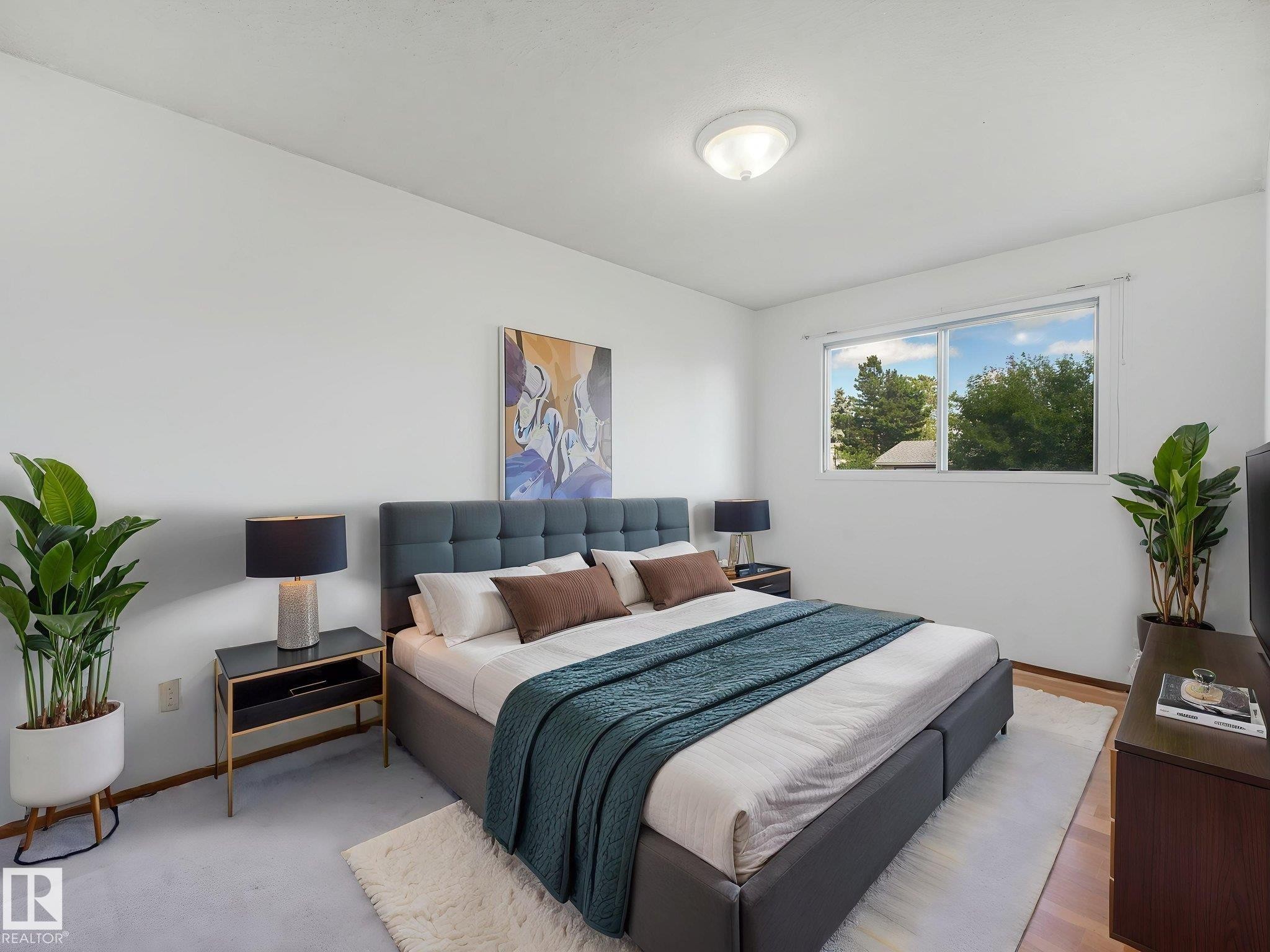 Light-filled room featuring a large window, light-toned walls, overhead flush mount lighting, and wood-finish flooring - 15011 72A Street, Edmonton, AB