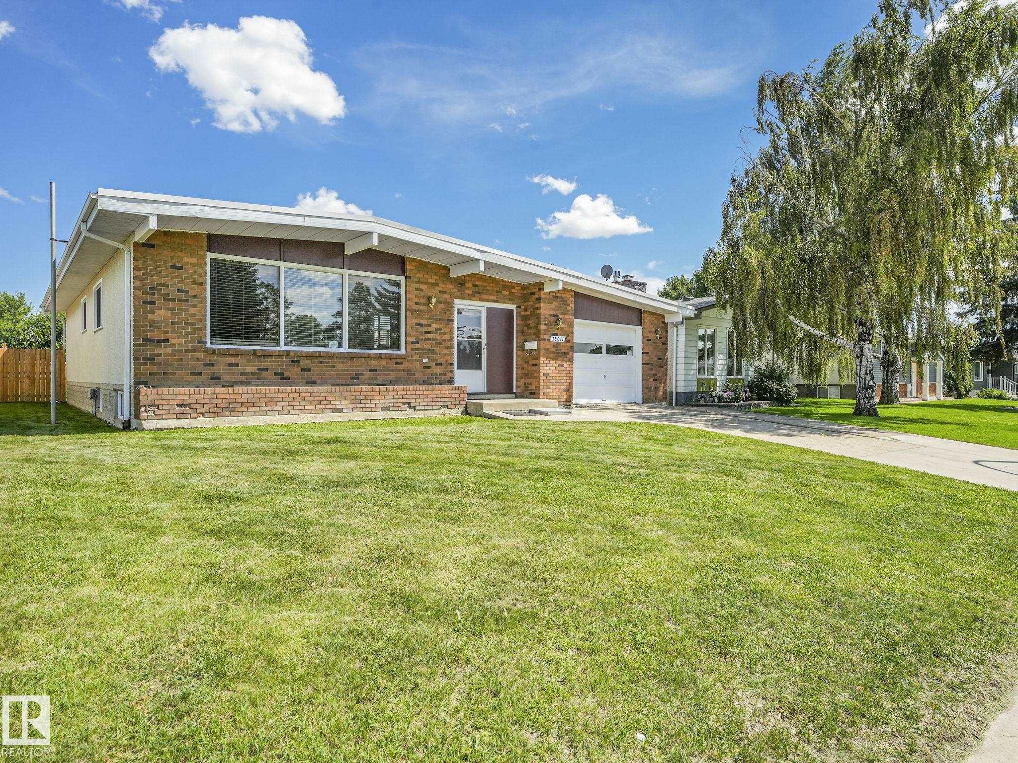 Ranch-style residence featuring a brick facade, integrated single-car garage, and a spacious front lawn - 15011 72A Street, Edmonton, AB