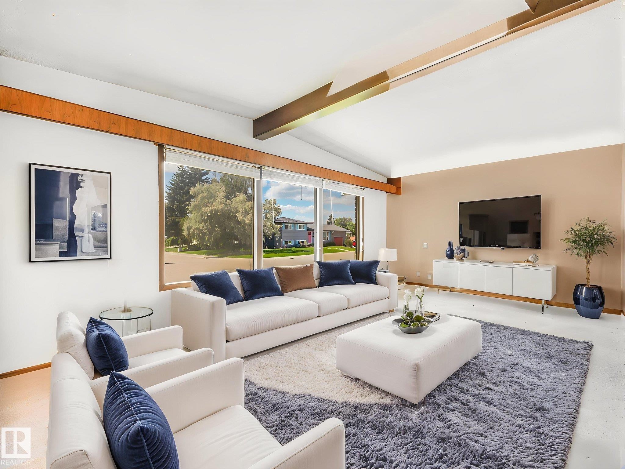 Vaulted ceiling with exposed wood beams, expansive windows, wood-finish flooring, and a neutral color palette create a bright, open living space - 15011 72A Street, Edmonton, AB