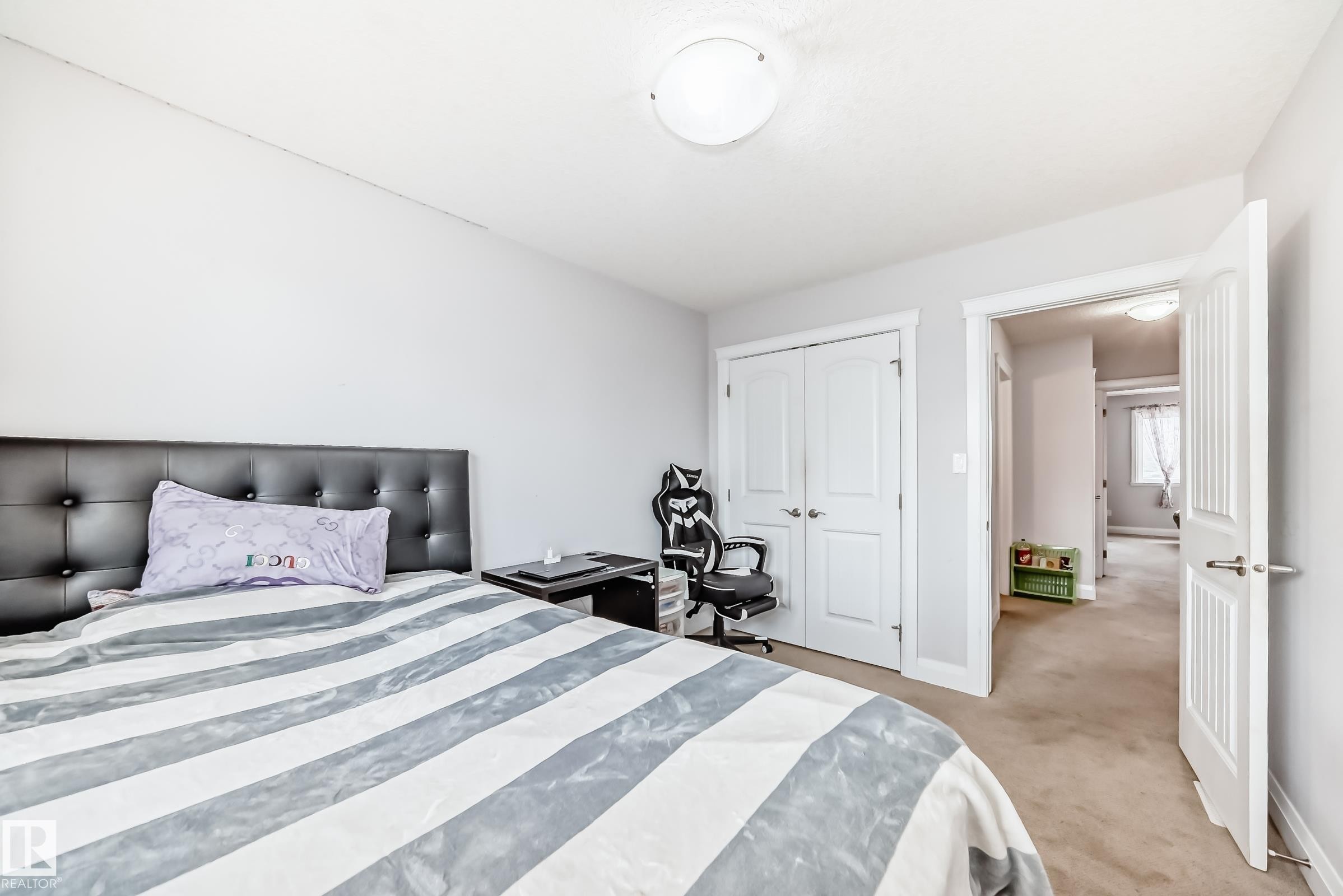 Bedroom featuring light gray walls, carpet flooring, a white trim doorway, and a double-door closet - #2 12042 101 St Nw, Edmonton, AB - Indoor Photo Showing Bedroom