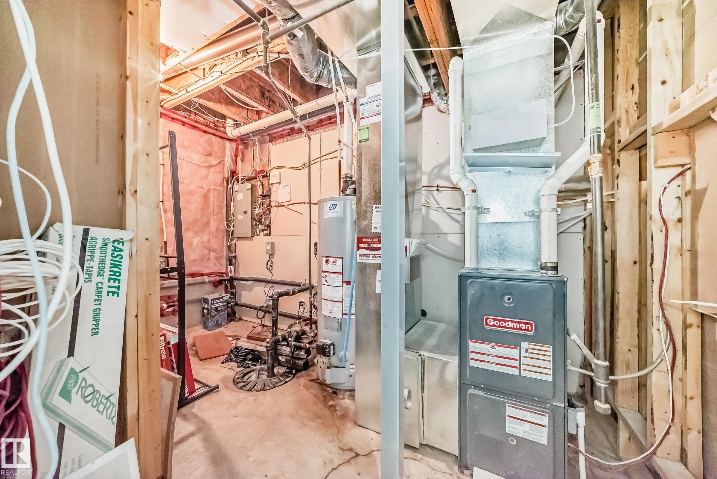 Mechanical room featuring a Goodman furnace, water heater, exposed ductwork, and electrical panel - #2 12042 101 St Nw, Edmonton, AB - Indoor Photo Showing Basement