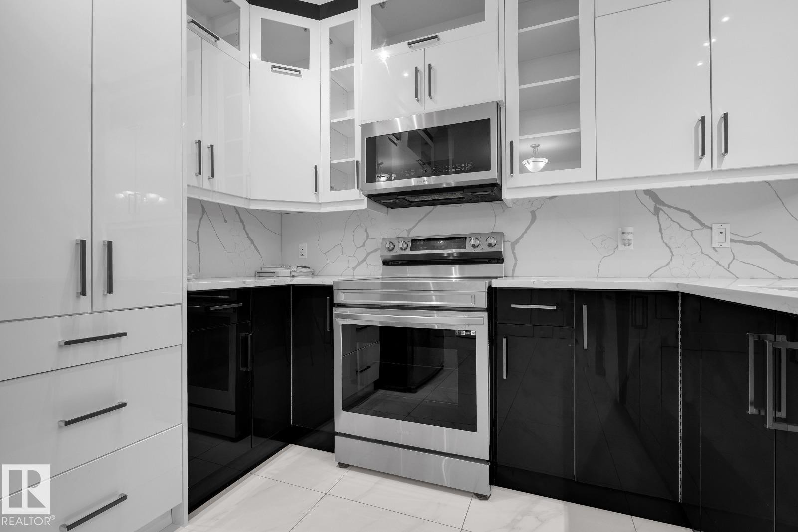 Modern kitchen featuring two-tone cabinetry with sleek hardware, a stainless steel range, and a matching microwave - 105 160 Magrath Road, Edmonton, AB