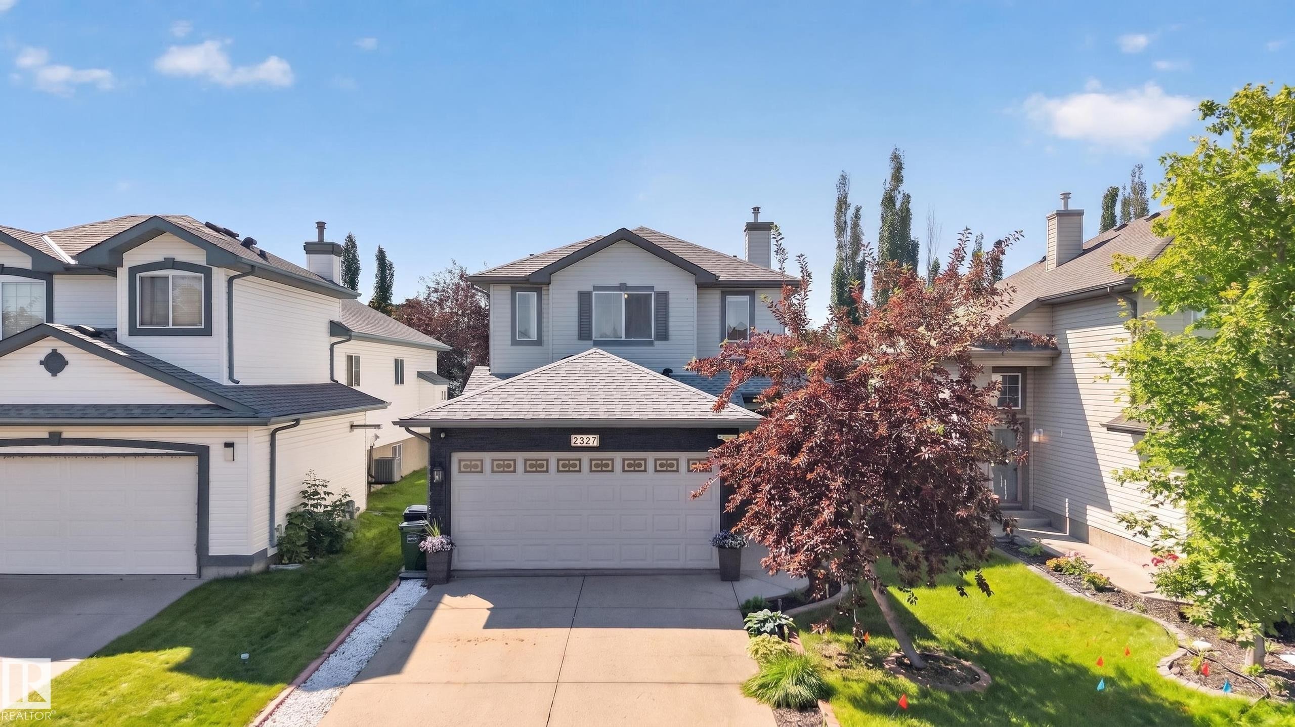 Contemporary two-story residence with a two-car garage, featuring a gabled roofline and light-colored siding with dark trim accents - 2327 37B Avenue, Edmonton, AB