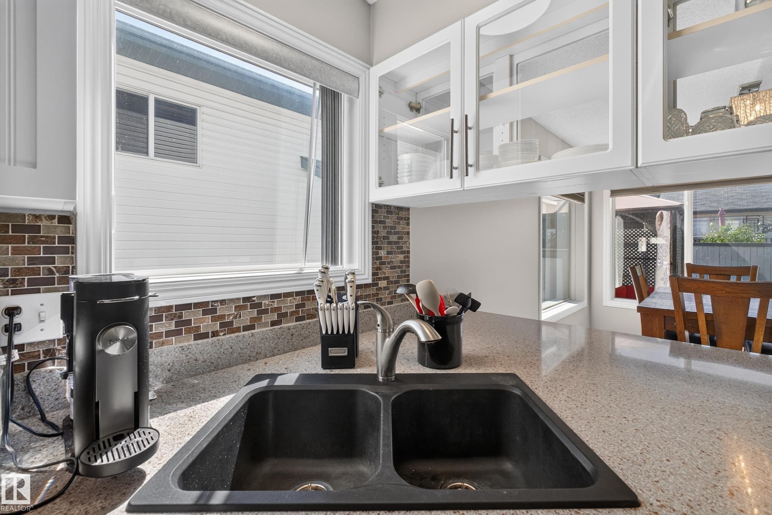 Kitchen sink with a dual basin, a high-arc faucet, and light-colored speckled countertops - 2327 37B Avenue, Edmonton, AB