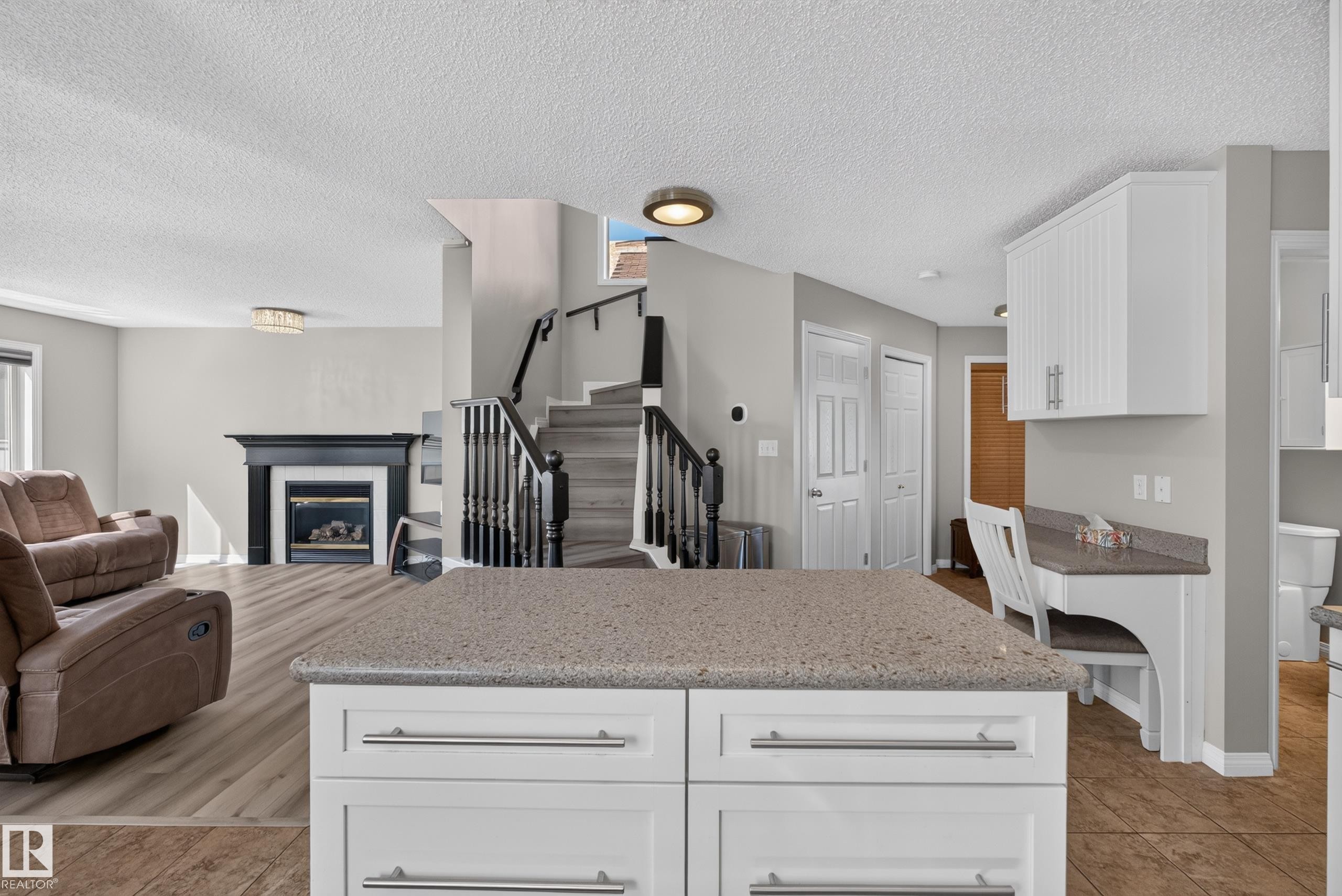 Kitchen island featuring a stone-finish countertop and white cabinetry with brushed nickel hardware - 2327 37B Avenue, Edmonton, AB