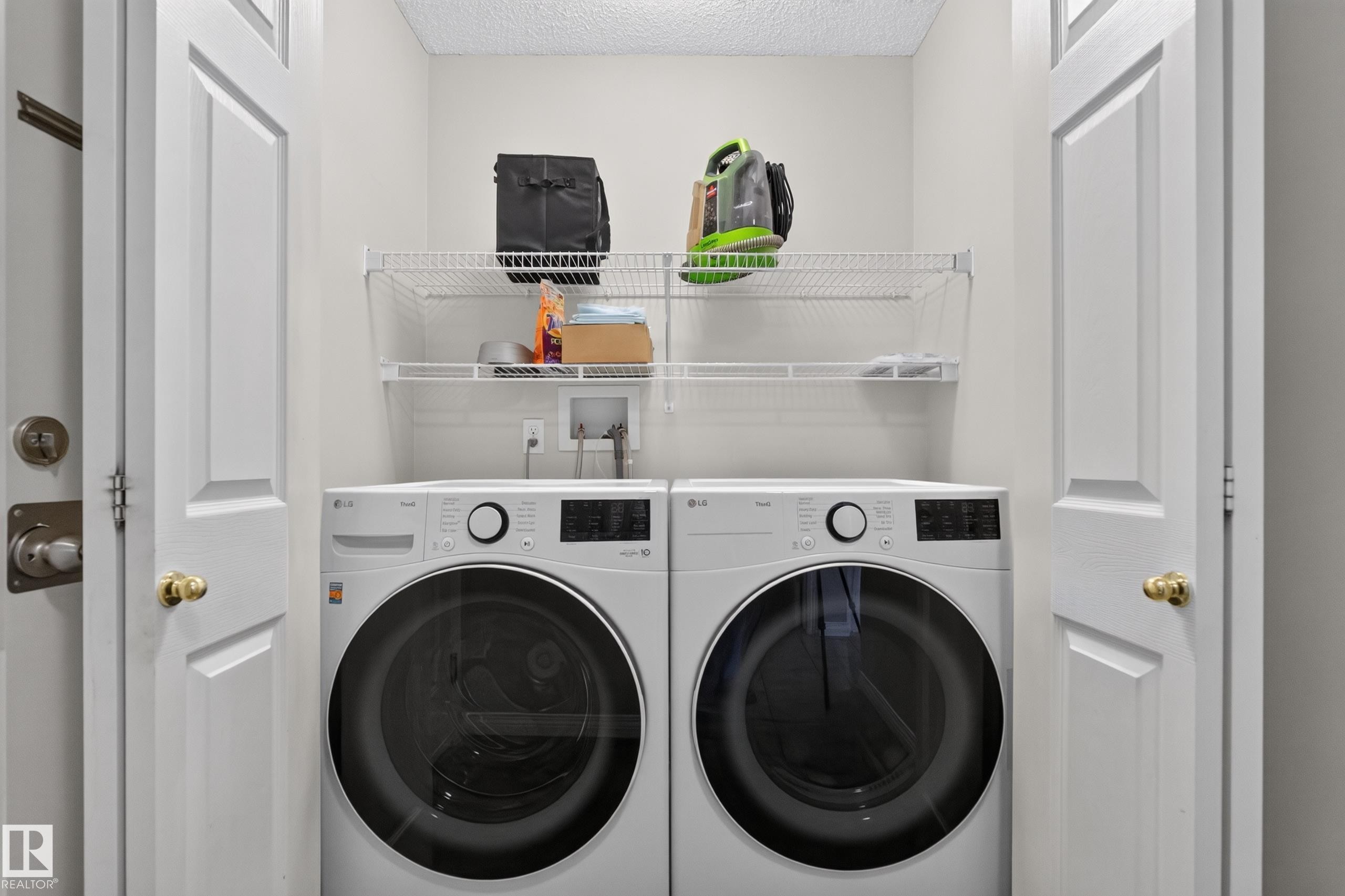 Dedicated laundry closet featuring a full-size washer and dryer, white wire shelving, and bi-fold doors - 2327 37B Avenue, Edmonton, AB