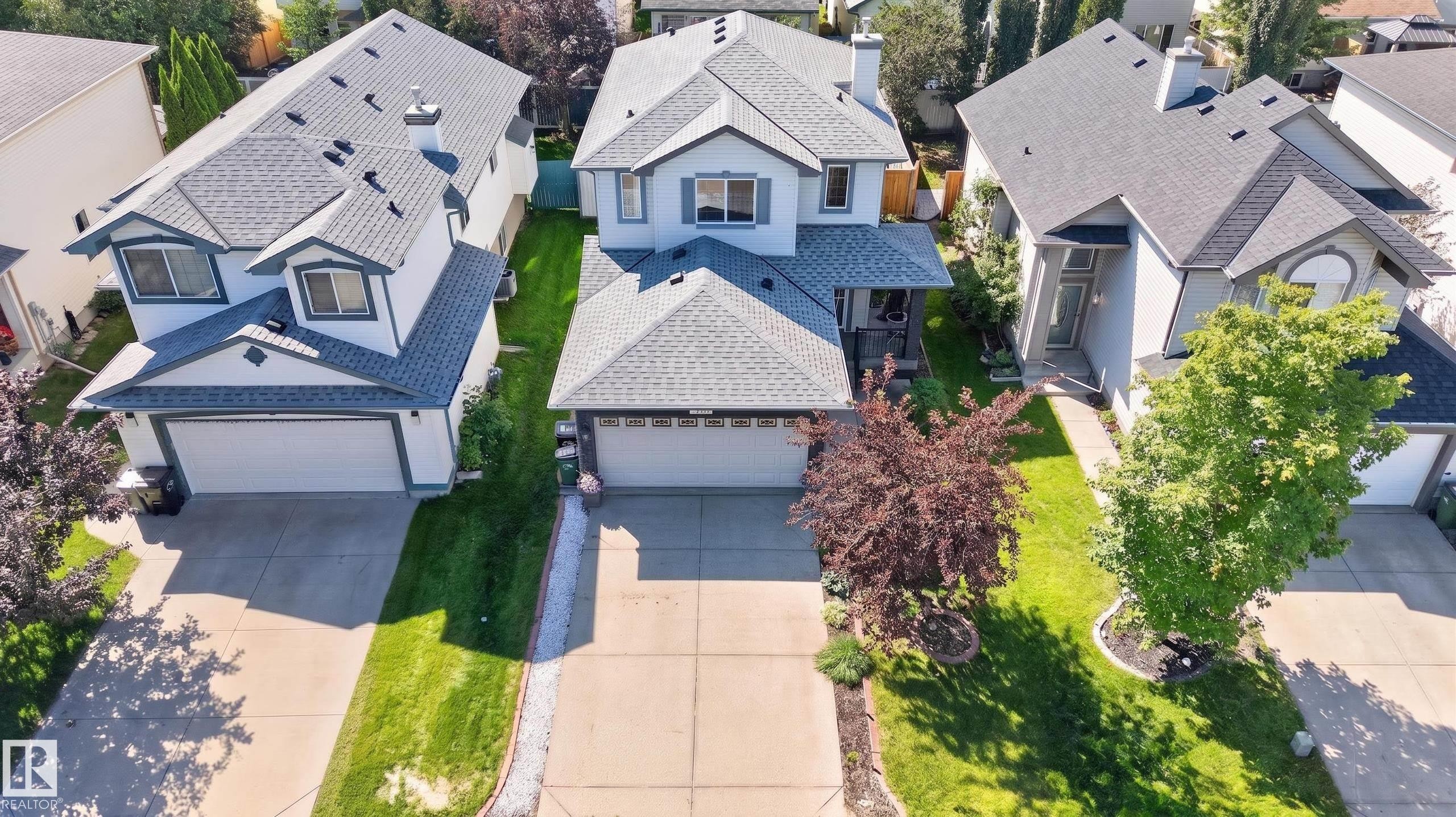 Contemporary two-story residence featuring a gray shingle roof, light-colored siding, and a prominent attached two-car garage - 2327 37B Avenue, Edmonton, AB