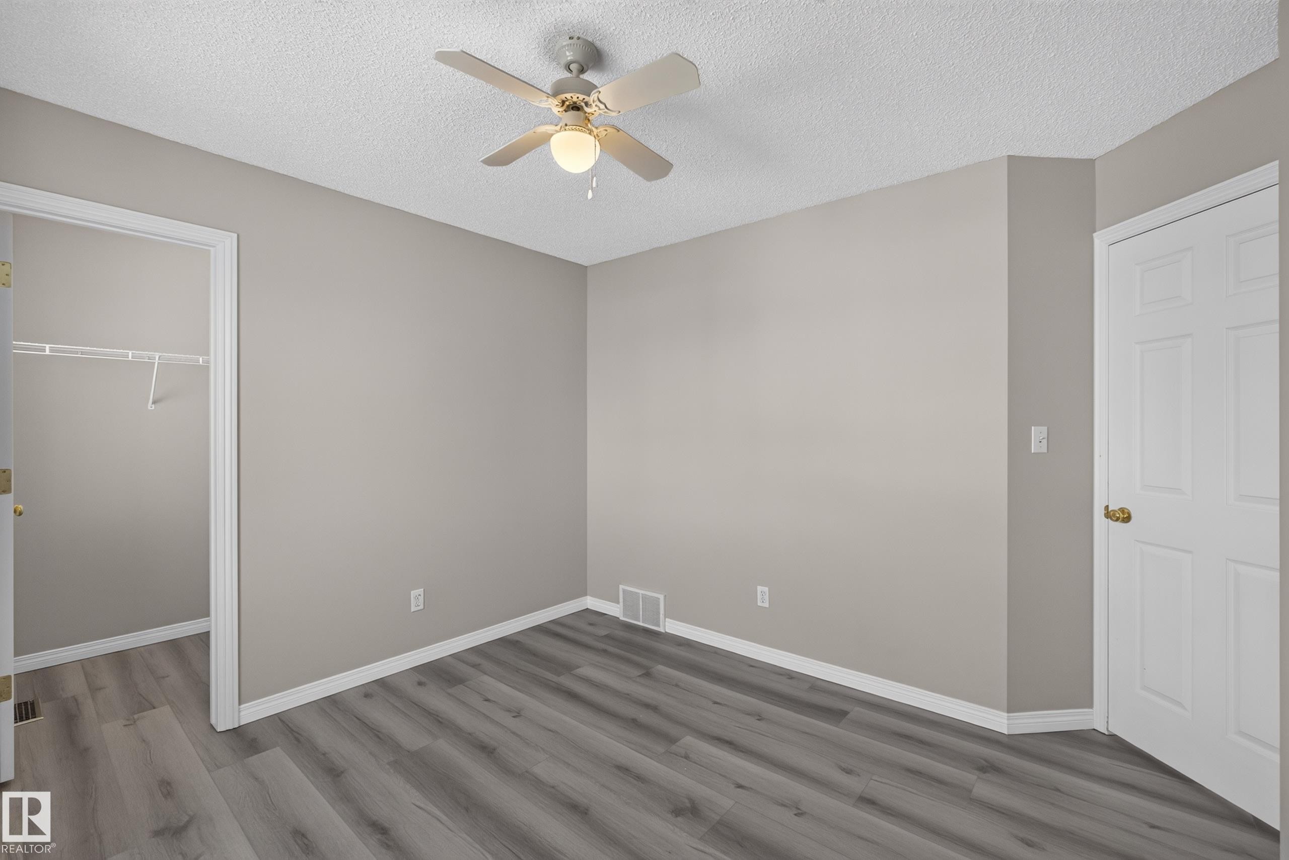 Neutral-toned walls complement wood-finish flooring in this room - 2327 37B Avenue, Edmonton, AB