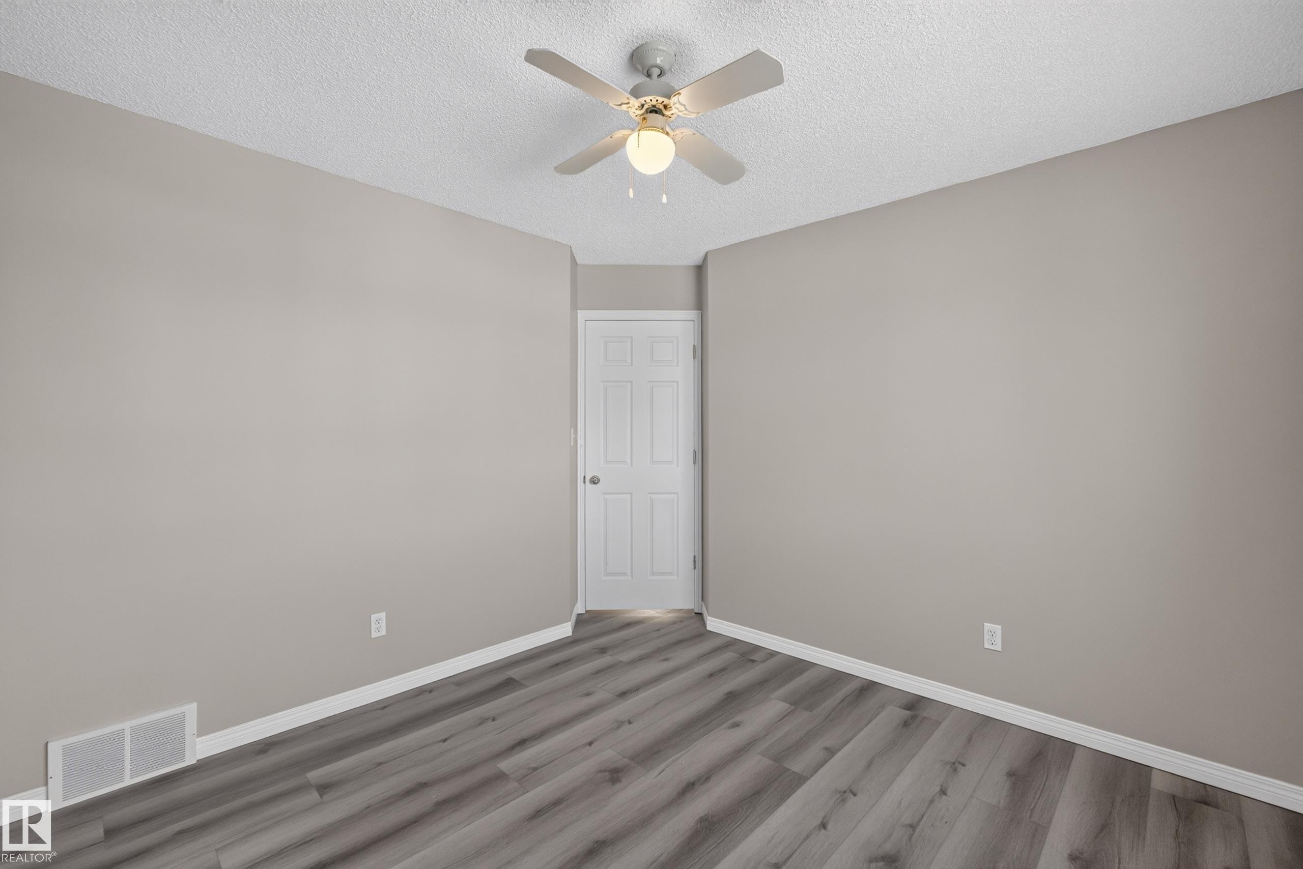 Interior room featuring wood-finish flooring, a ceiling fan with integrated lighting, and a paneled door - 2327 37B Avenue, Edmonton, AB