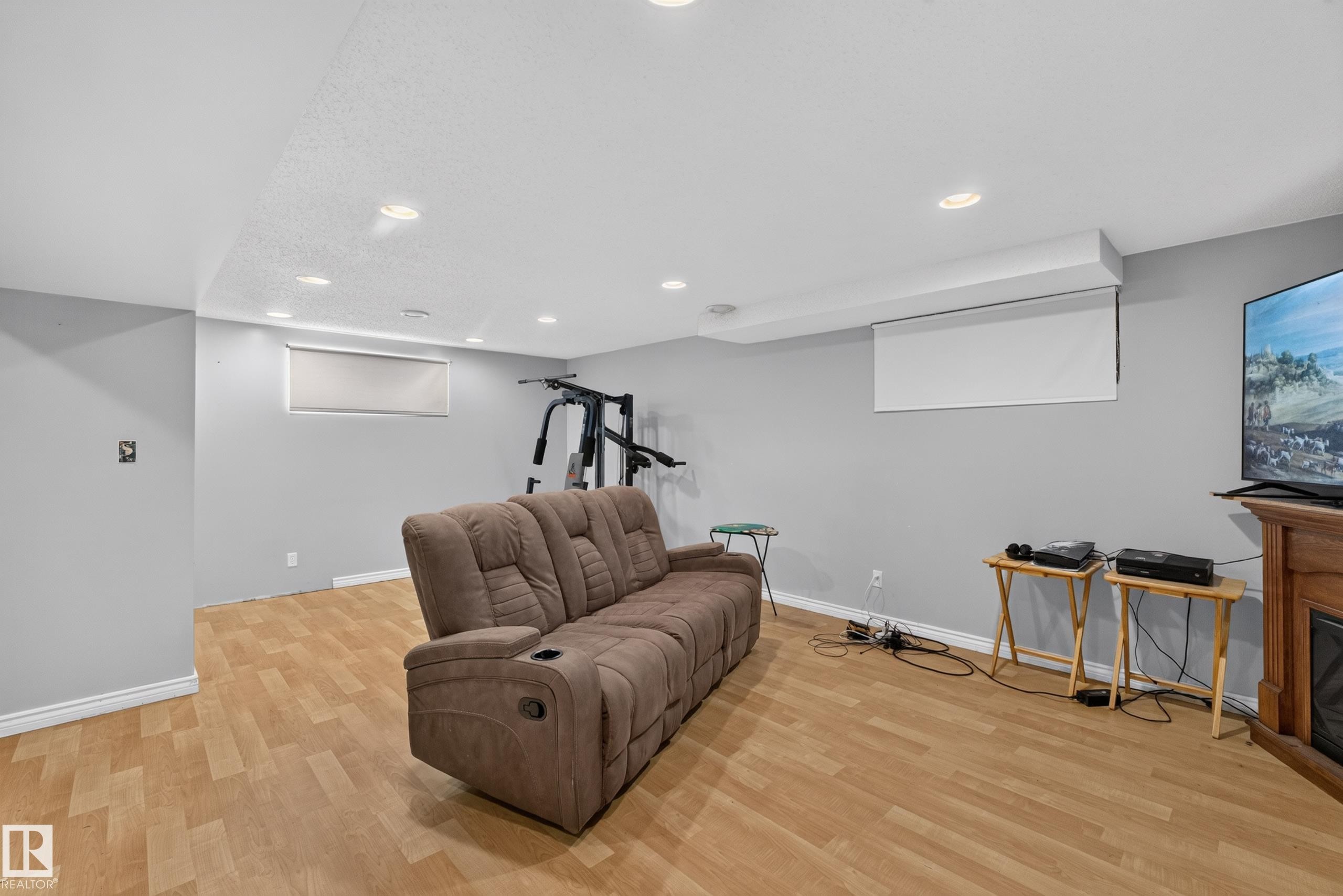 Spacious recreation room featuring light wood-finish flooring, recessed lighting, and a built-in projection screen - 2327 37B Avenue, Edmonton, AB