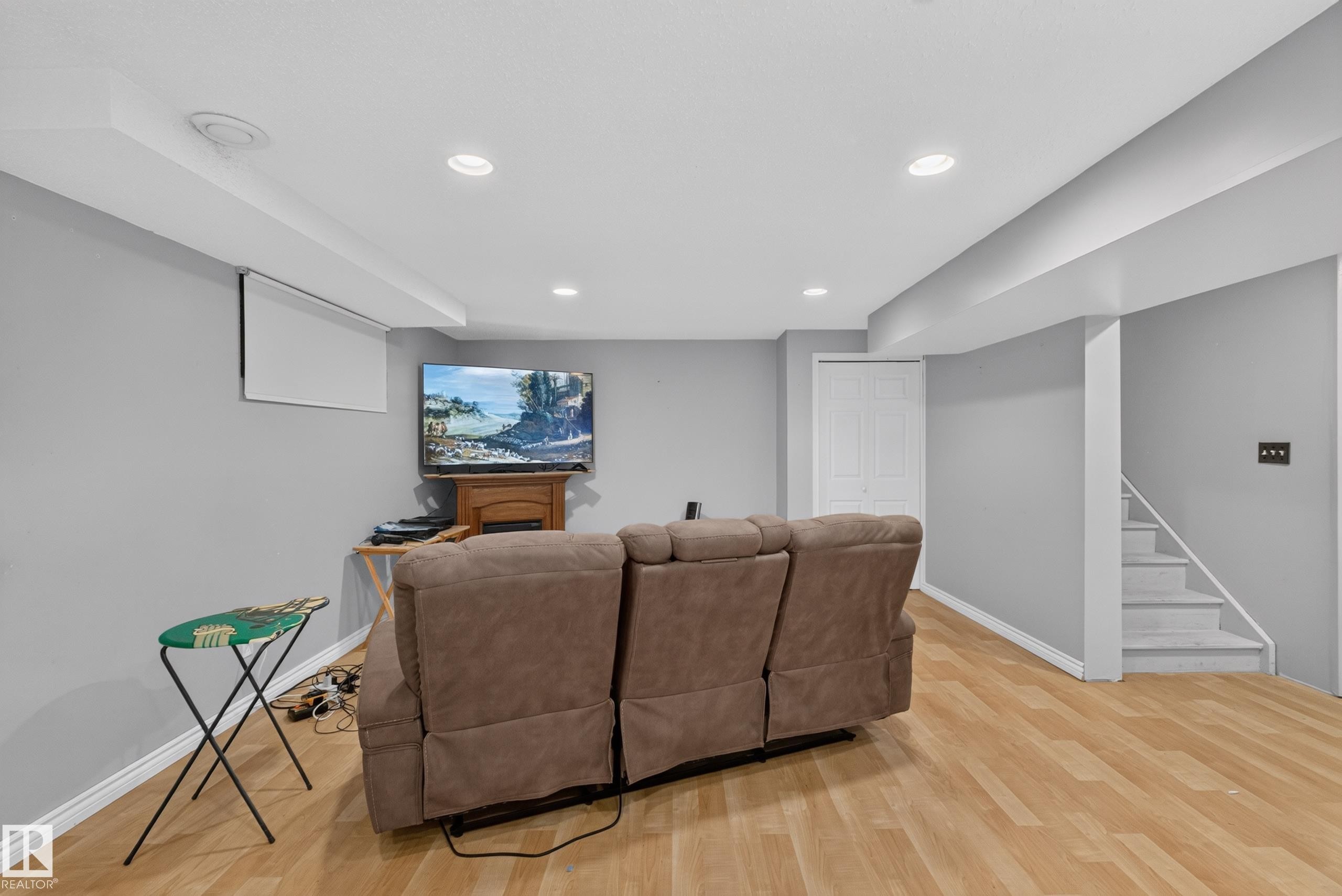 Spacious room featuring wood-finish flooring, recessed lighting, light gray walls, and white trim - 2327 37B Avenue, Edmonton, AB