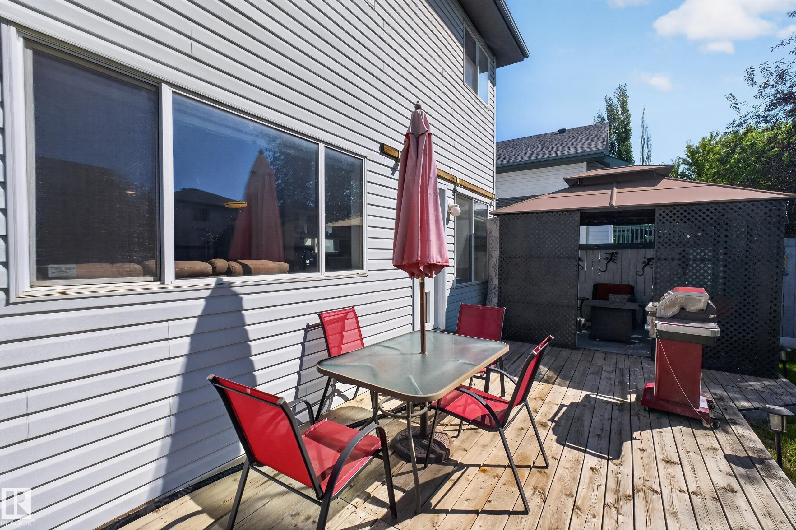 Spacious wood-finish deck featuring a dedicated gazebo area, horizontal siding, and large windows - 2327 37B Avenue, Edmonton, AB