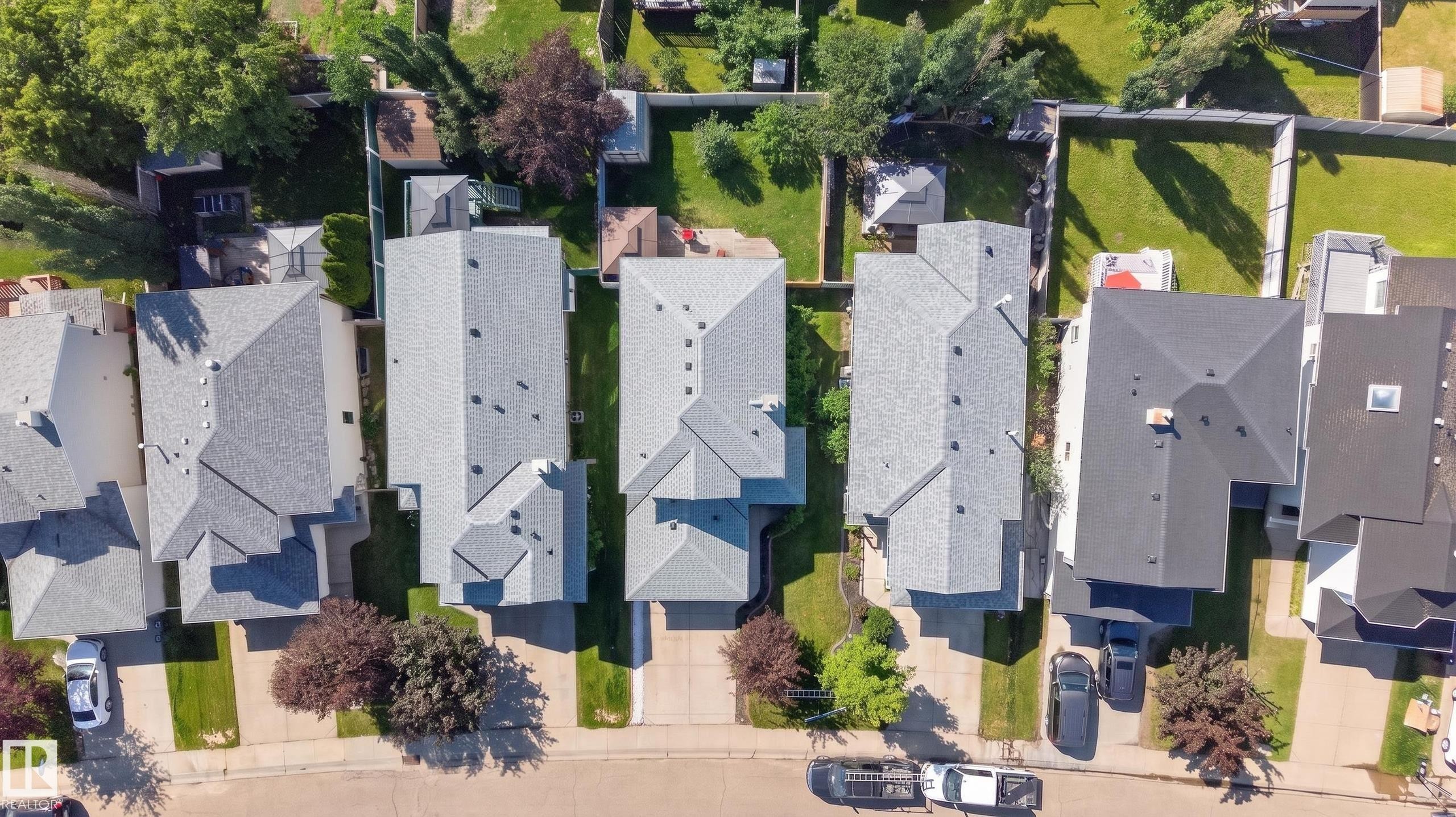 Aerial perspective of a residential street featuring multiple properties with pitched shingle roofs and established landscaping - 2327 37B Avenue, Edmonton, AB