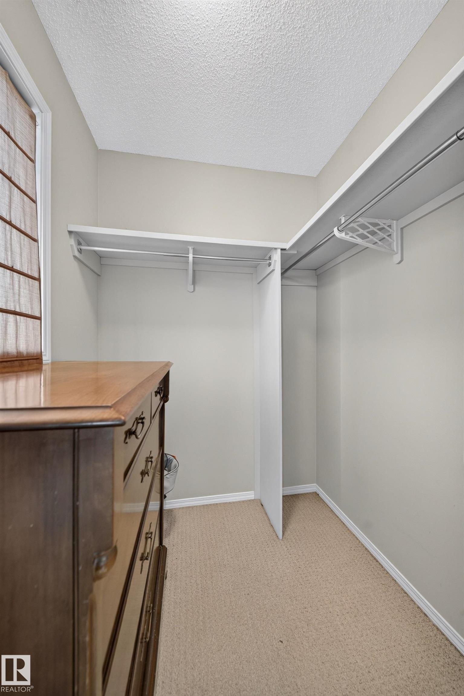 Walk-in closet featuring built-in shelving, hanging rods, and neutral carpet flooring - 59 2503 24 Street, Edmonton, AB
