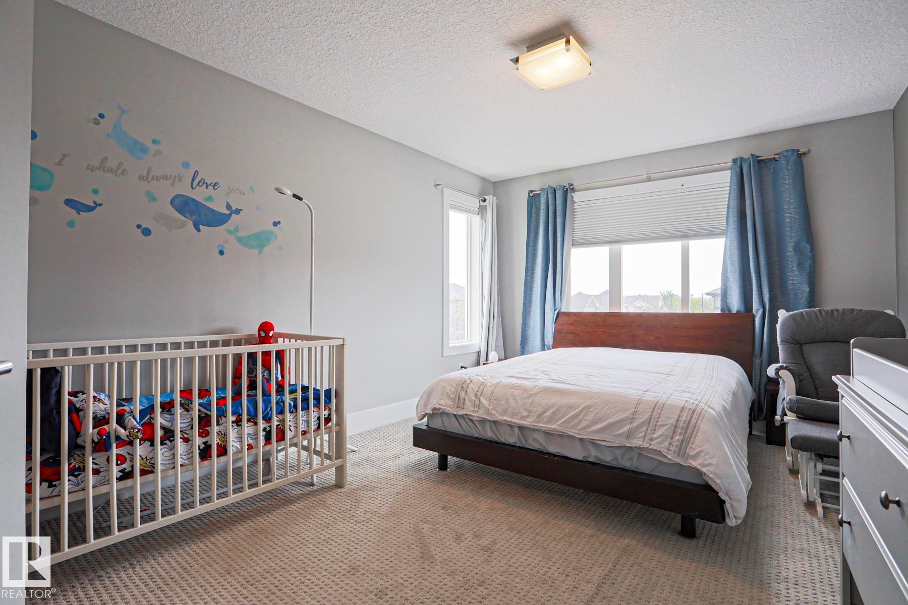 Carpeted room featuring a window with blinds, ceiling-mounted light fixture, and light gray walls - 1304 Ainslie Wynd Sw, Edmonton, AB - Indoor Photo Showing Bedroom