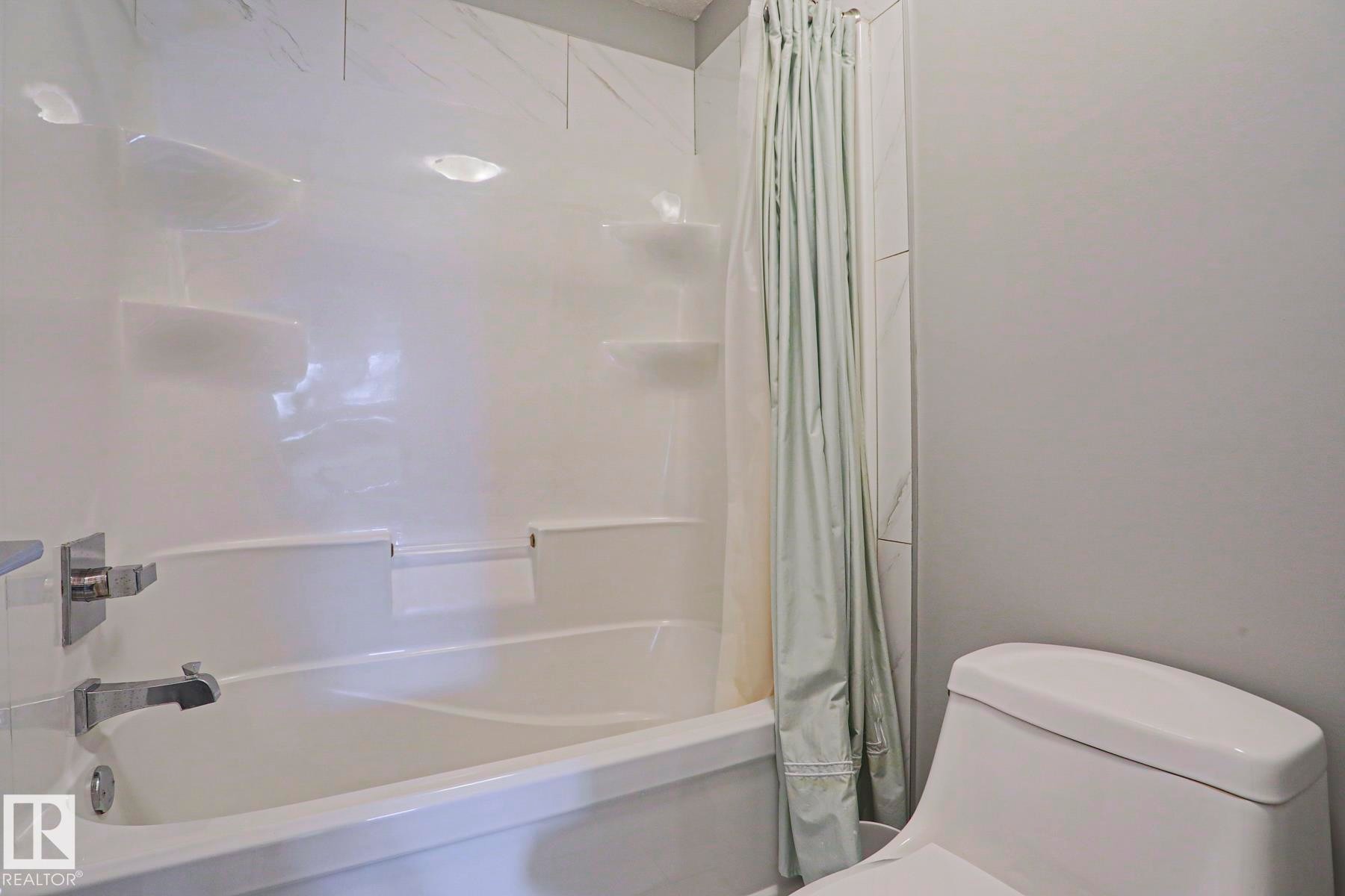 White acrylic tub and shower combination with integrated shelving - 1304 Ainslie Wynd Sw, Edmonton, AB - Indoor Photo Showing Bathroom