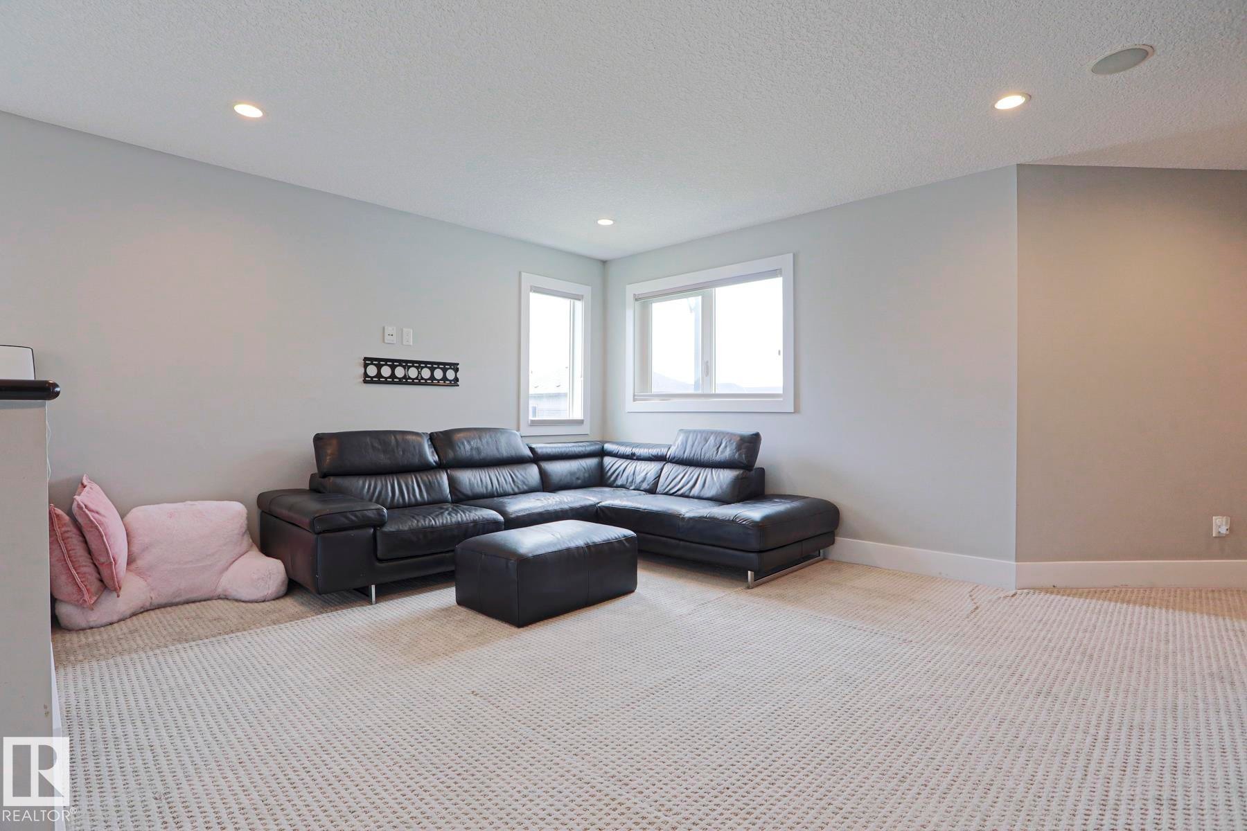 Spacious room featuring light gray walls, white trim, recessed lighting, and two windows providing natural light - 1304 Ainslie Wynd Sw, Edmonton, AB - Indoor Photo Showing Living Room