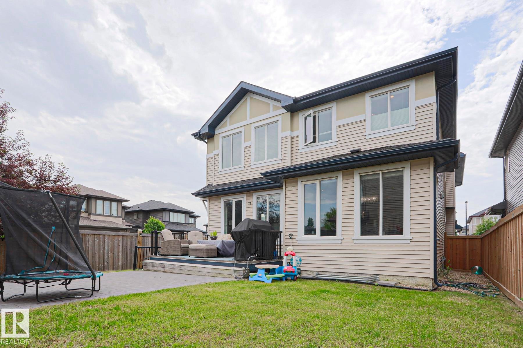 Expansive backyard featuring a green lawn and a large composite deck - 1304 Ainslie Wynd Sw, Edmonton, AB - Outdoor With Exterior