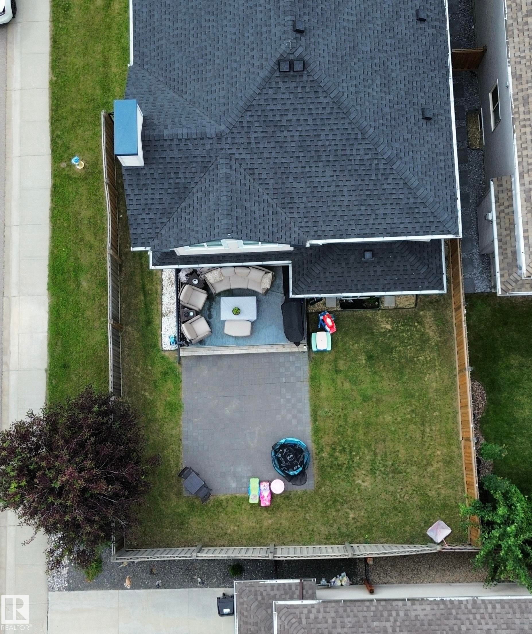 Spacious backyard featuring a large patio area with paver stones and a substantial lawn - 1304 Ainslie Wynd Sw, Edmonton, AB - Outdoor