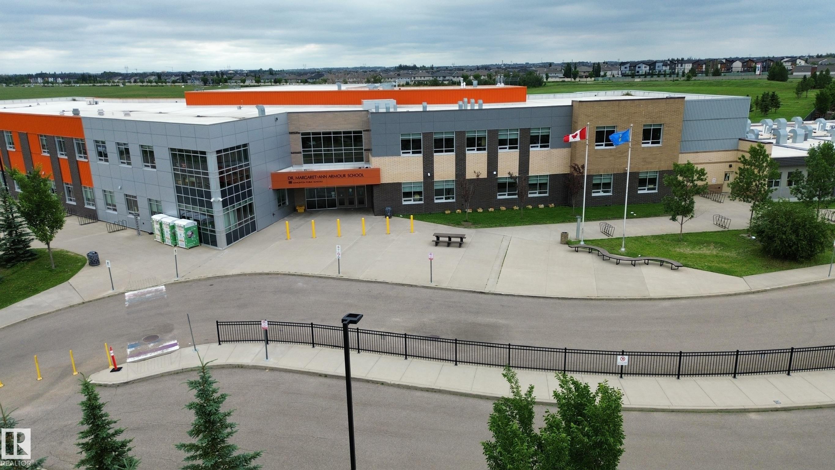 Contemporary multi-story commercial building featuring orange, gray, and tan exterior panels - 1304 Ainslie Wynd Sw, Edmonton, AB - Outdoor