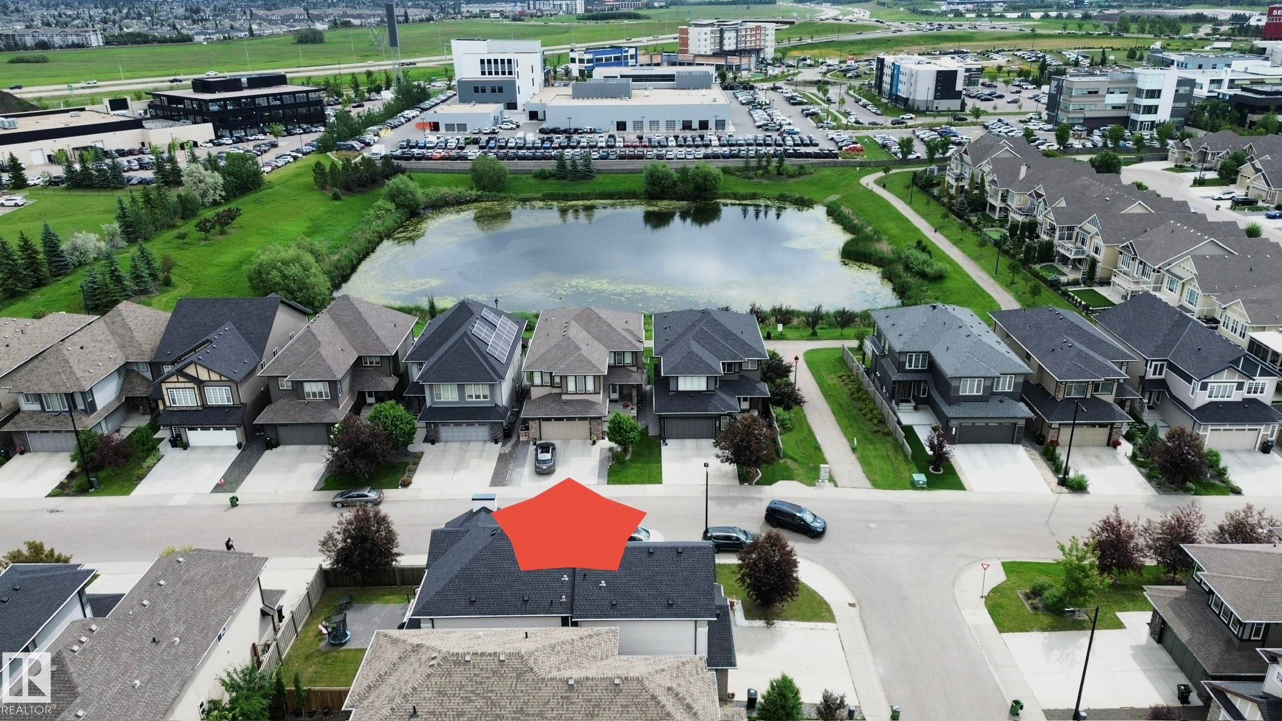 Residential property featuring a shingled roof, attached garage, and paved driveway - 1304 Ainslie Wynd Sw, Edmonton, AB - Outdoor With View