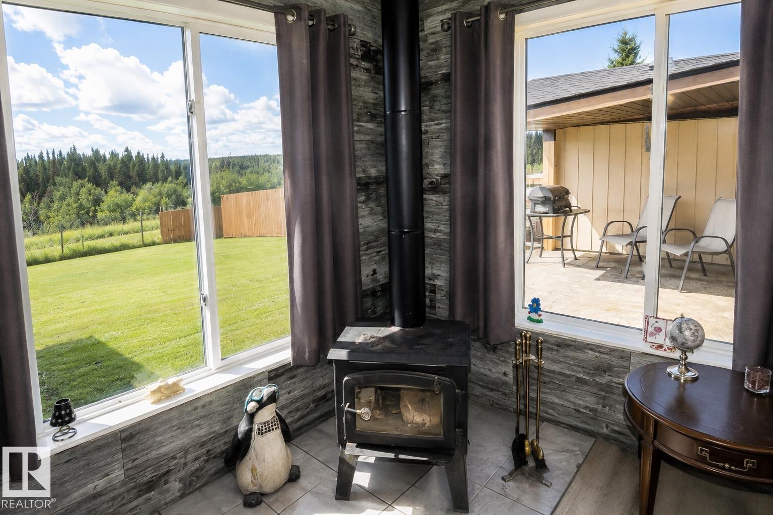 Ceiling fan with light fixture, sliding glass door, rich wood cabinetry, concrete flooring, and exposed ceiling beams - 315 57201 Rng Rd 102, Rural St. Paul County, AB