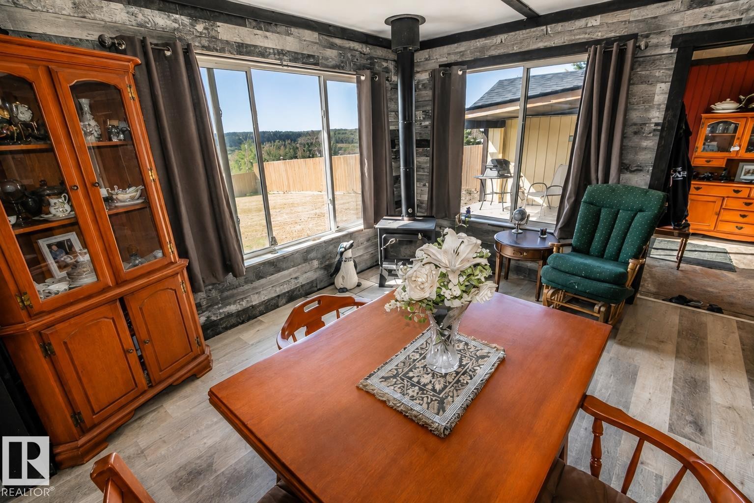 Wood-finish flooring, accent wall with horizontal paneling, painted red walls, black trim, and a window with dark curtains - 315 57201 Rng Rd 102, Rural St. Paul County, AB