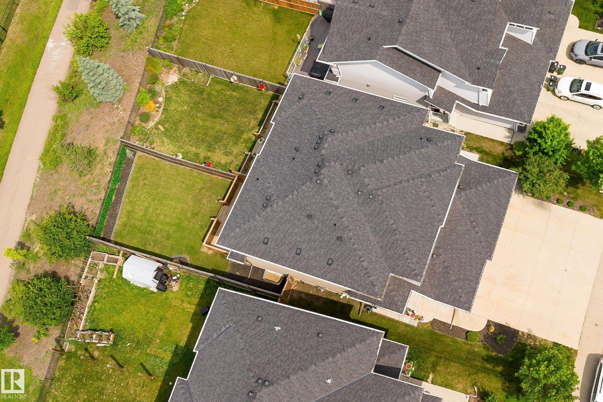 Aerial view showcasing architectural rooflines with dark shingles, landscaped grounds, and paved driveway access - 8589 Cushing Place Sw, Edmonton, AB - Outdoor