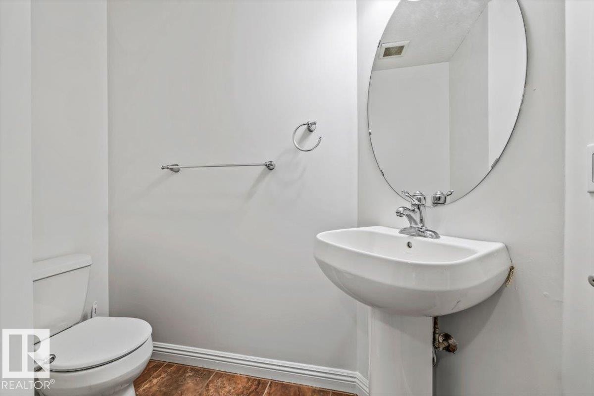 Pedestal sink with chrome fixtures and an oval mirror - 2407 Hagen Way, Edmonton, AB