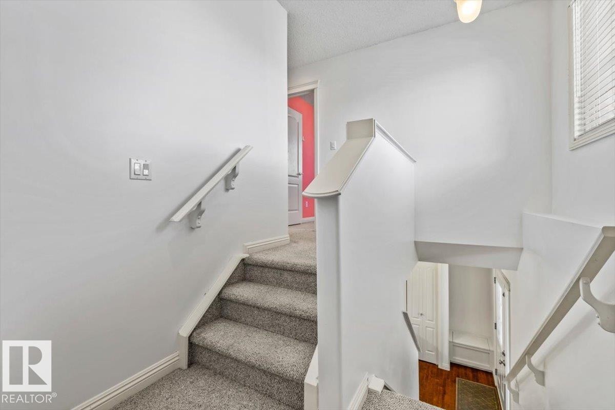 Carpeted staircase with white handrails and painted balustrades - 2407 Hagen Way, Edmonton, AB