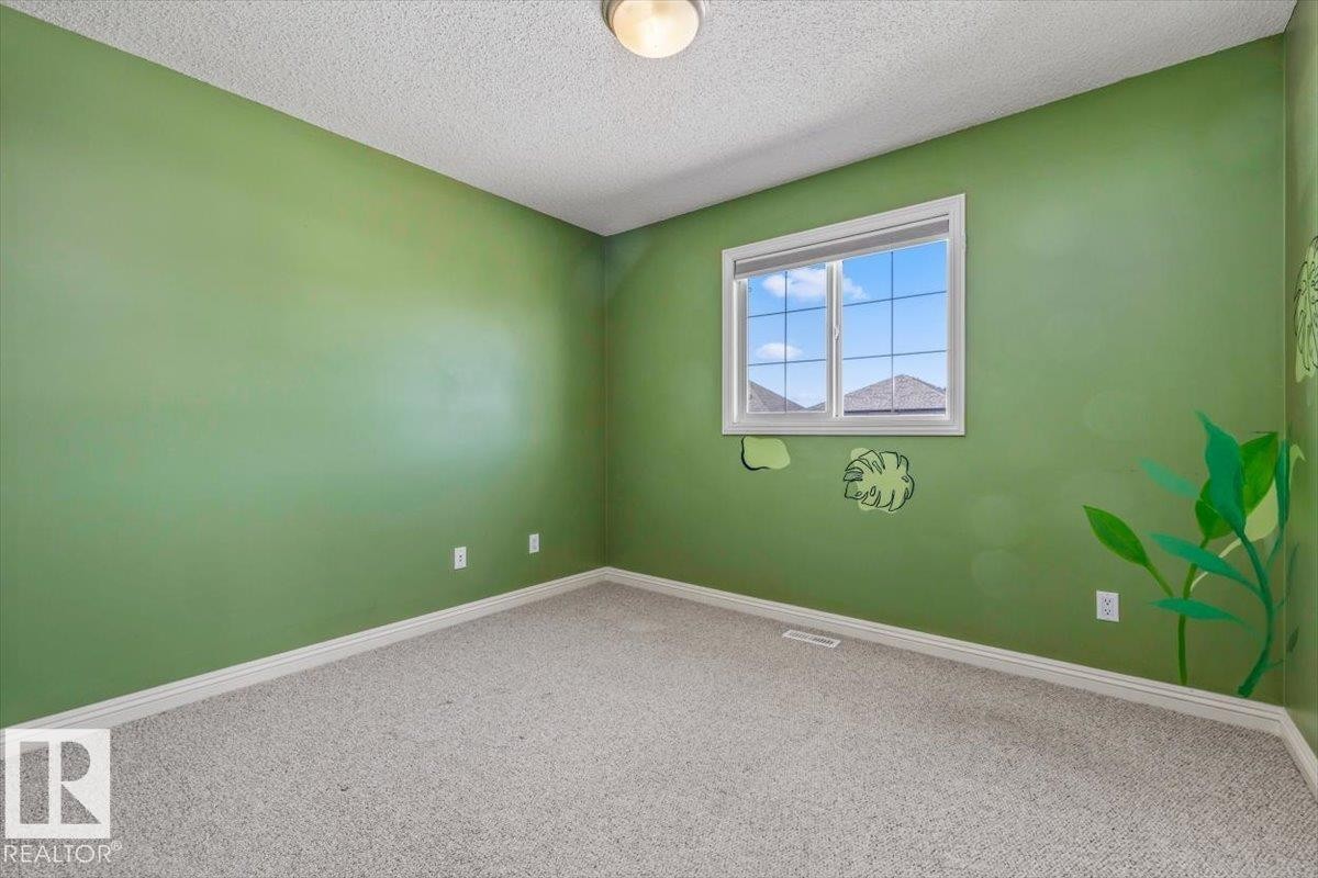 Carpeted room featuring a single window with white trim, baseboard molding, and a flush mount ceiling light fixture - 2407 Hagen Way, Edmonton, AB