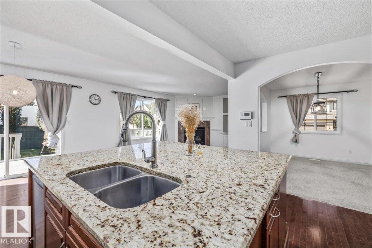 Kitchen island with a double basin stainless steel sink and gooseneck faucet - 2407 Hagen Way, Edmonton, AB